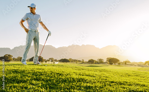 Young man with golf stick on field