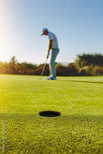 Professional golfer putting ball in hole