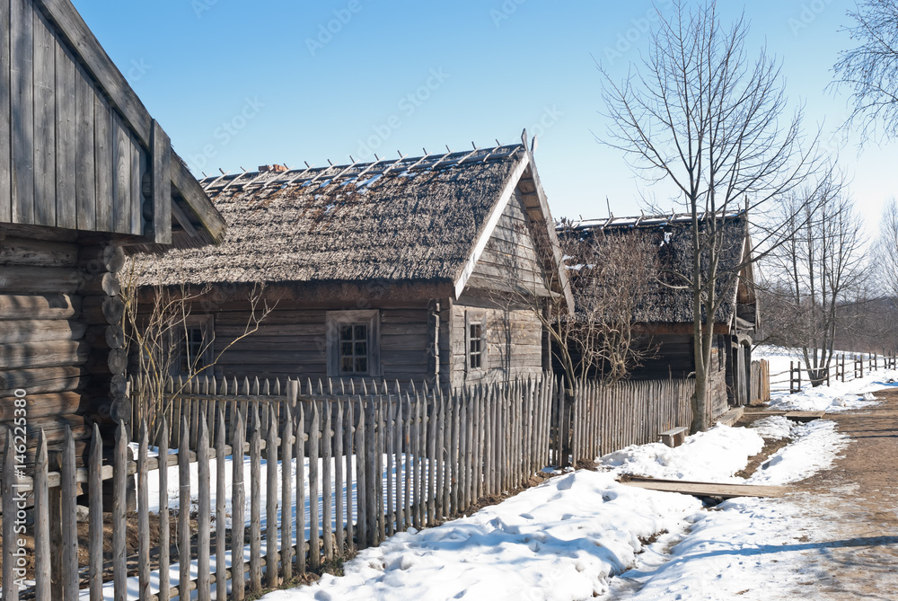 Fototapeta premium Spring in the village from the past. Ancient log huts with thatched roofs