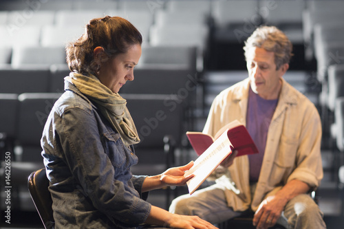 Caucasian actors rehearsing with scripts in theater