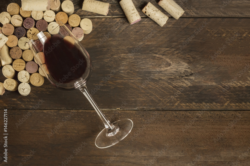 Glass of red wine and corks on dark background