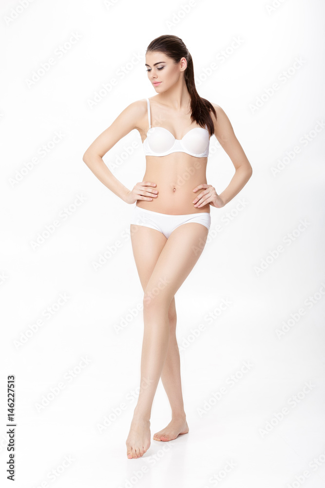 beautiful young brunette woman with perfect sporty body in white lingerie on white background. Full length portrait beautiful young brunette woman with perfect sporty body in white lingerie on white background. Full length portrait