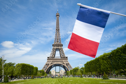 French flag flying in front of the Eiffel Tower on a bright summer day