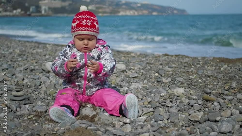 Cute little girl playing on the beach with pebbles, slow motion hd video Cute little girl playing on the beach with pebbles, slow motion hd video