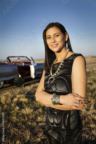 Portrait of smiling woman standing in grass near car photo
