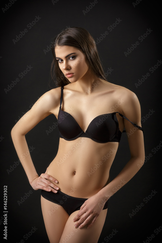 beautiful sexy brunette woman posing in black lingerie on black background. Seductive and attractive slim shapely body 