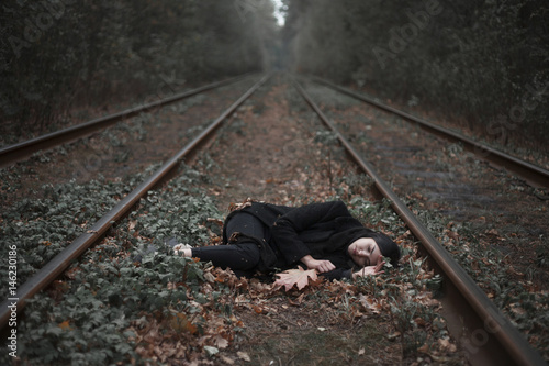 Caucasian woman laying between railroad tracks