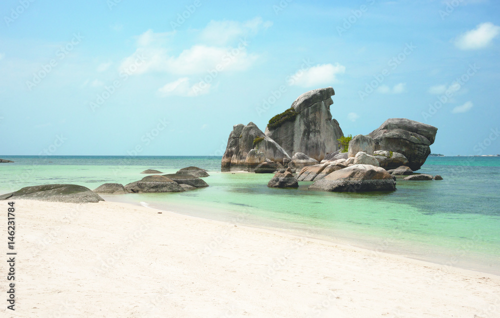 Natural rock formation in the sea and on a white sand beach in Belitung Island in the afternoon, Indonesia.