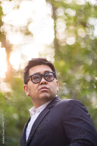 A man in black suit and white shirt pose in the forest with vision eyes expression