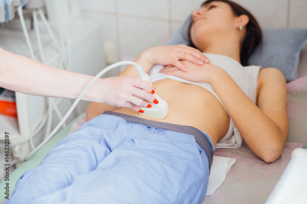 Fototapeta premium Young woman undergoing ultrasound scan in clinic