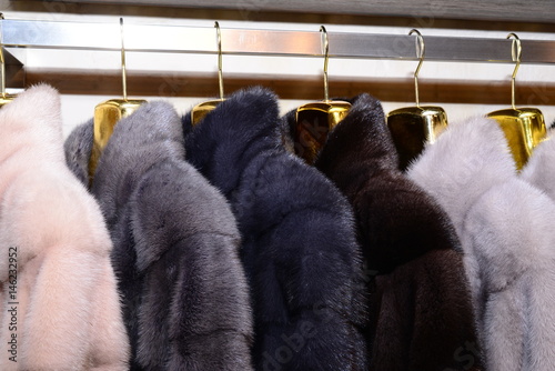 Luxury mink coats. Pink, grey, dark grey, pearl color fur coats on showcase of market. Best gift for a woman. Outerwear. Close up.
