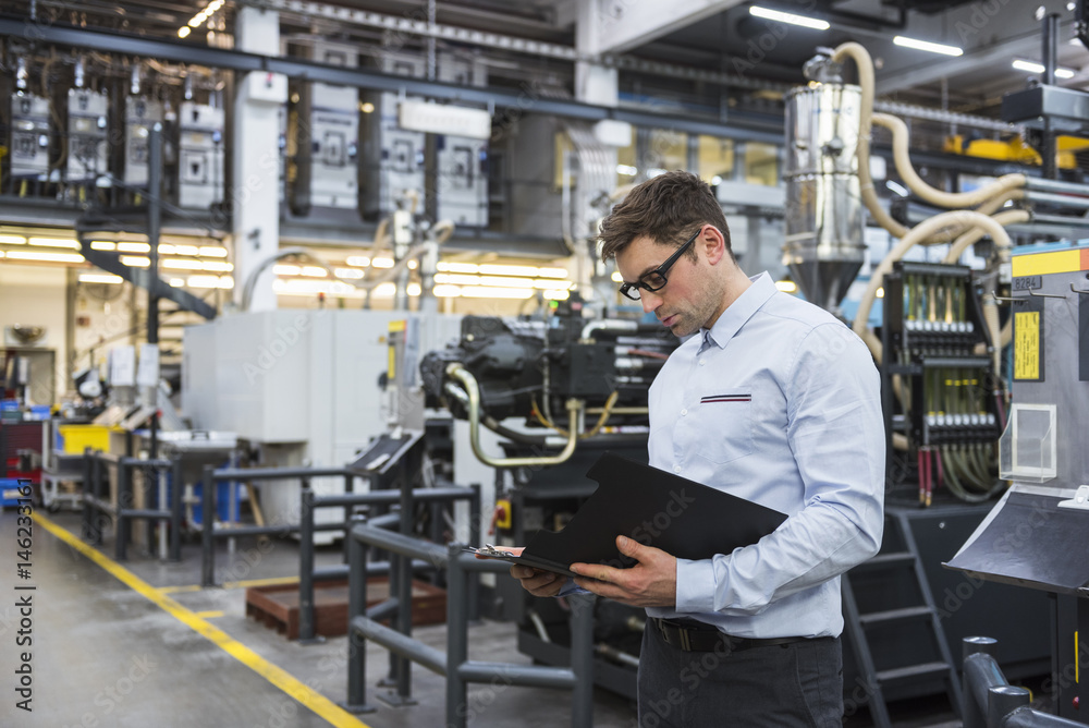 Man looking at documents in factory shop floor Man looking at documents in factory shop floor