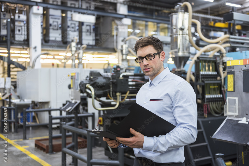 Portrait of man holding documents in factory shop floor Portrait of man holding documents in factory shop floor