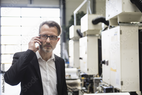 Businessman in factory shop floor on the phone