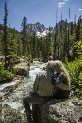 Caucasian couple hugging on rock at mountain river photo
