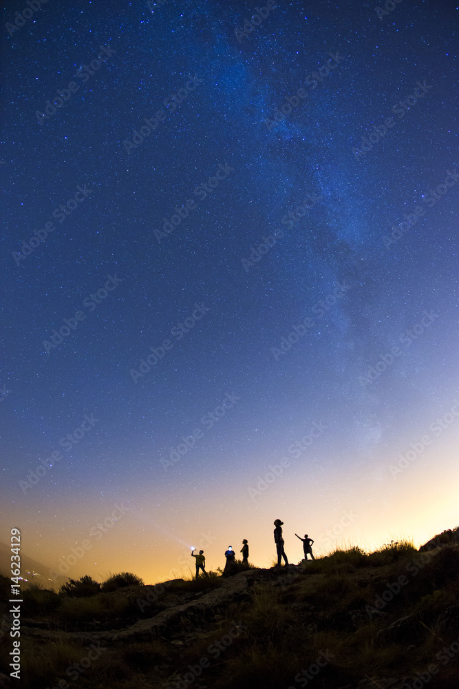 Silhouette of the person on the high rock at Milky Way background