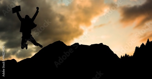 Silhouette businessman jumping on mountain during sunset
