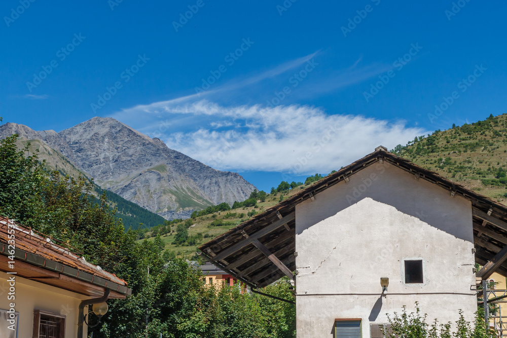 Travelling in Italian Alps - Little alpine town house Highly in mountains at hot shiny summer morning with blue cloudy sky