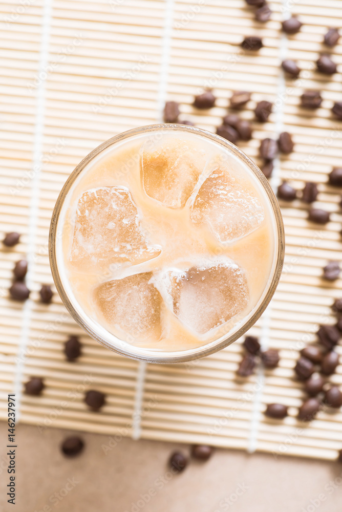 Glass of ice coffee with coffee bean on wooden background