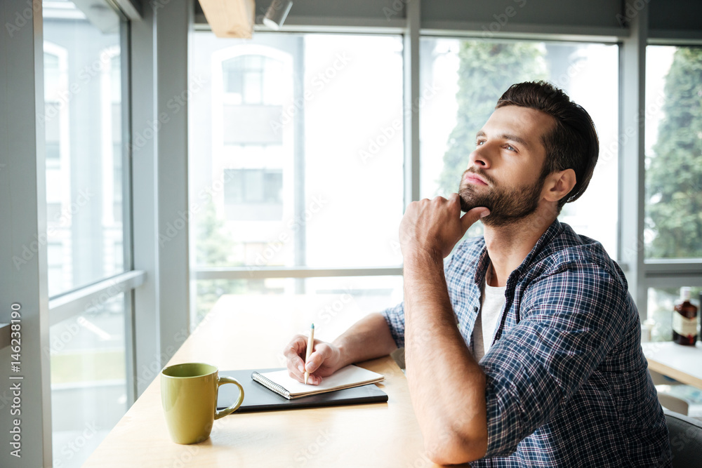 Thinking man in office coworking while writing notes Thinking man in office coworking while writing notes