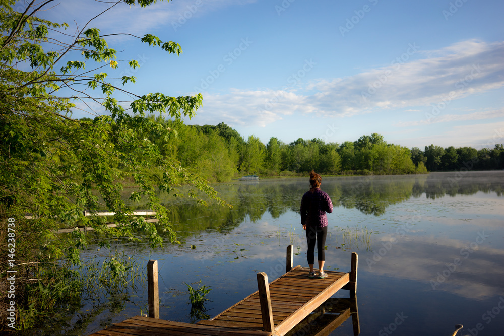 A woman looks out on a tranquil lake