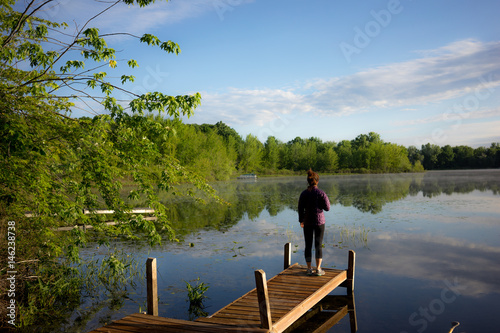 A woman looks out on a tranquil lake