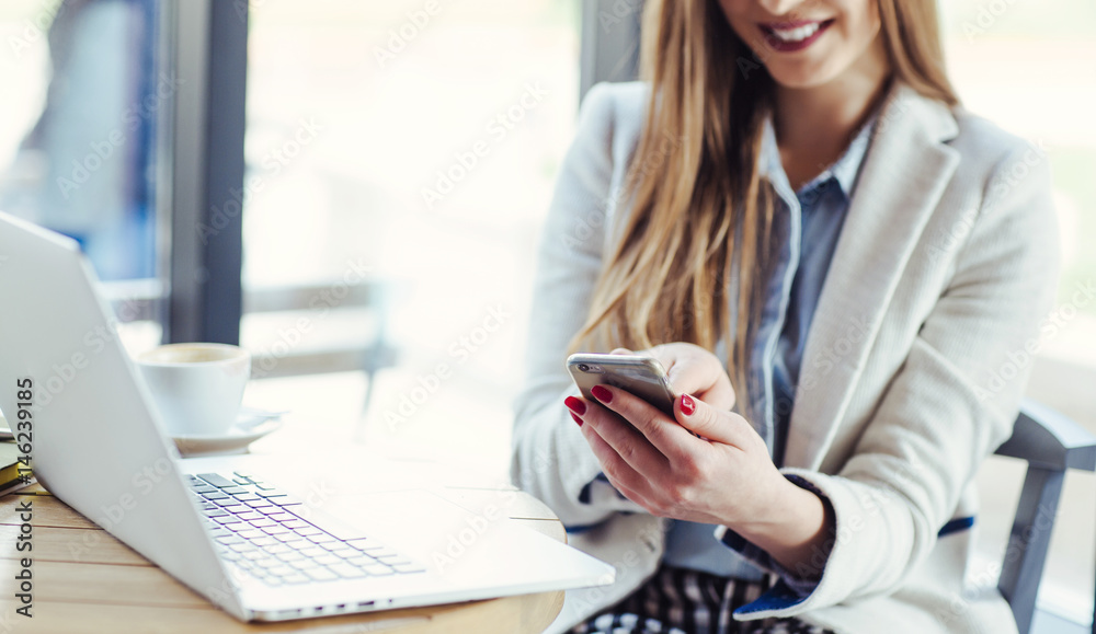 Obraz premium Woman Working on Laptop and Using Phone