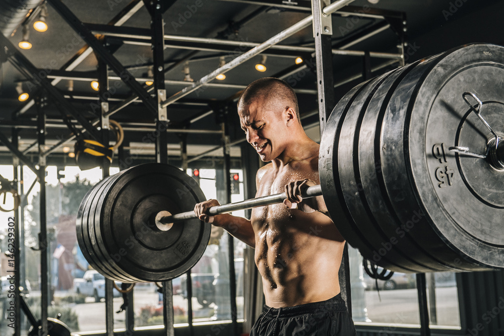 Man lifting heavy barbell in gymnasium Man lifting heavy barbell in gymnasium