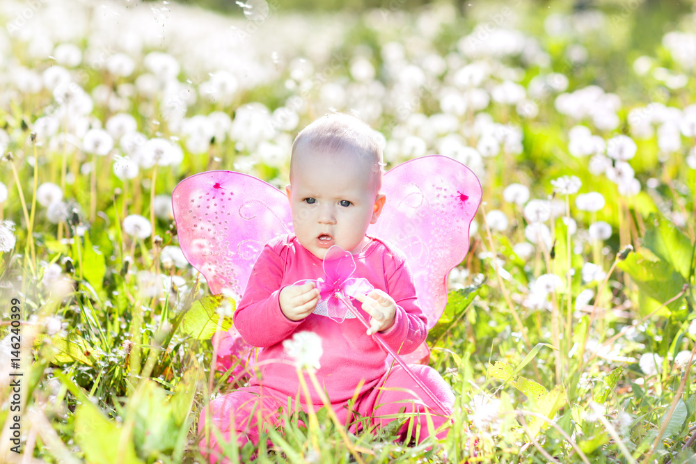 Child with pink wings sitting among dandelions Child with pink wings sitting among dandelions