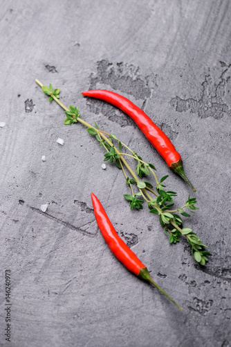 Chili pepper and fresh thyme on a gray concrete background