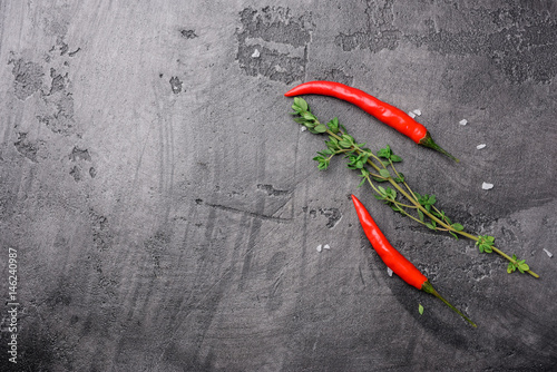 Chili pepper and fresh thyme on a gray concrete background, top view with copy space