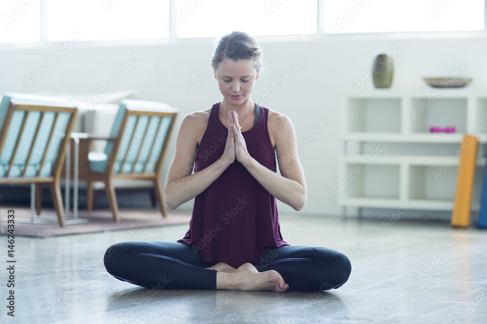 Caucasian woman sitting on floor meditating Caucasian woman sitting on floor meditating