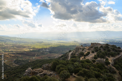 Ancient knights fortress and amazing Upper Galilee mountains view, North Israel. Evening shot. Big grey rain clouds. Sunlight rays and shadows on the hills.