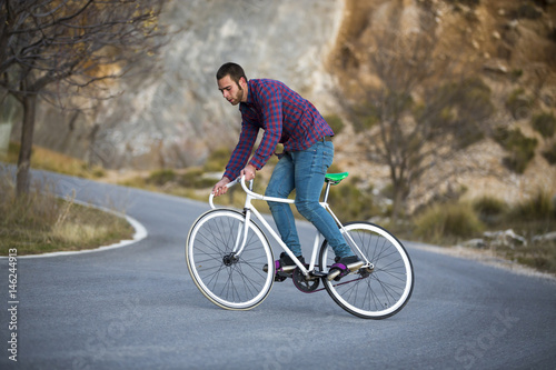 Fototapeta Naklejka Na Ścianę i Meble -  Cyclist man riding fixed gear sport bike in sunny day on a mountain road