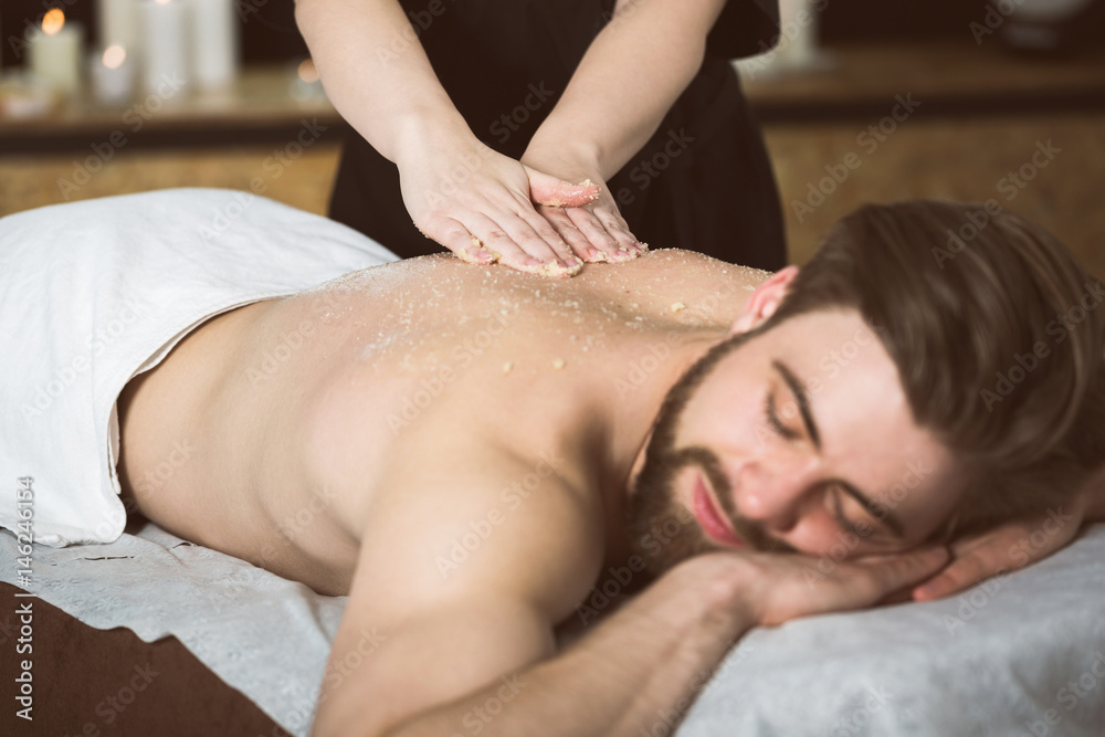 Fototapeta premium Man relaxing during a salt scrub beauty therapy