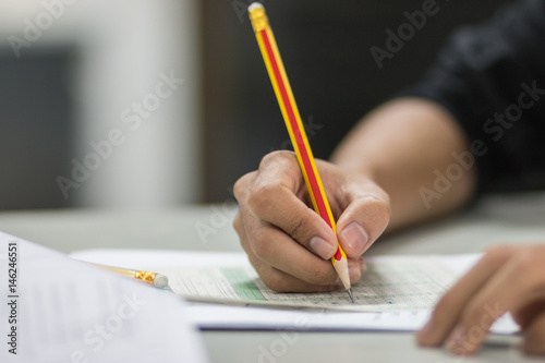 students hand testing doing examination with pencil drawing selected choice on answer sheets in school exam at college