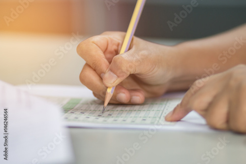 students hand testing doing examination with pencil drawing selected choice on answer sheets in school exam at college