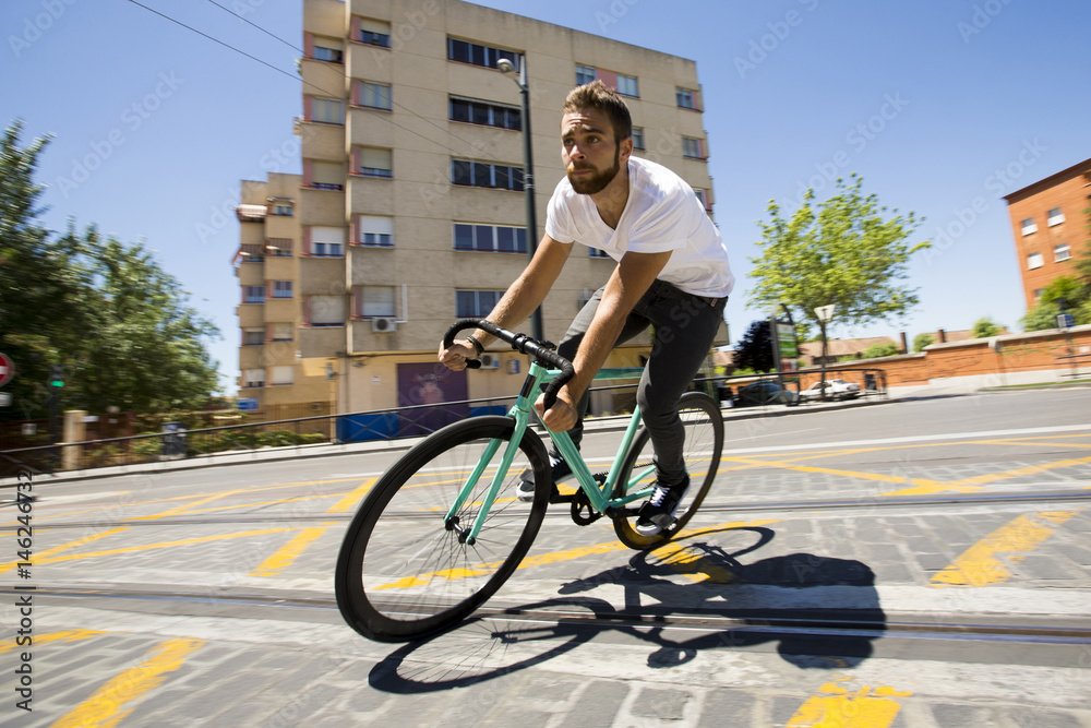 Naklejka premium Cyclist man riding fixed gear sport bike in sunny day on a city