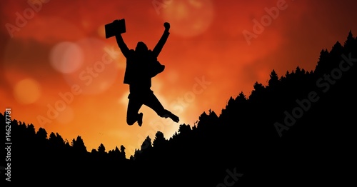 Silhouette businessman in midair against orange sky
