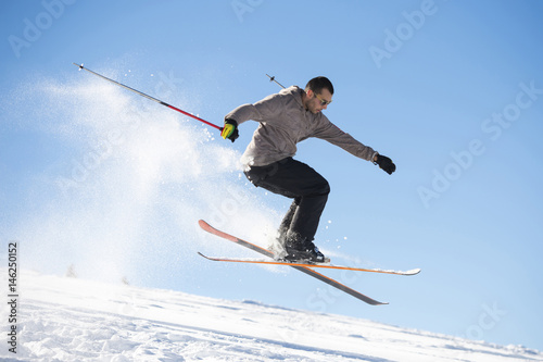 Freestyle ski jumper with crossed skis in snowy mountains