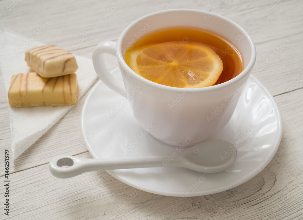 A cup of tea with lemon on a wooden table A cup of tea with lemon on a wooden table