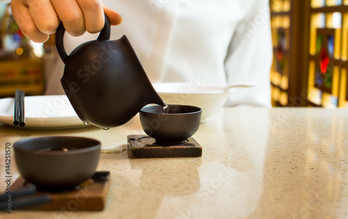 Female pouring tea into ceramic teacup