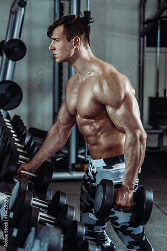 Strong muscular bodybuilder doing exercise in the gym. Part of fitness body.