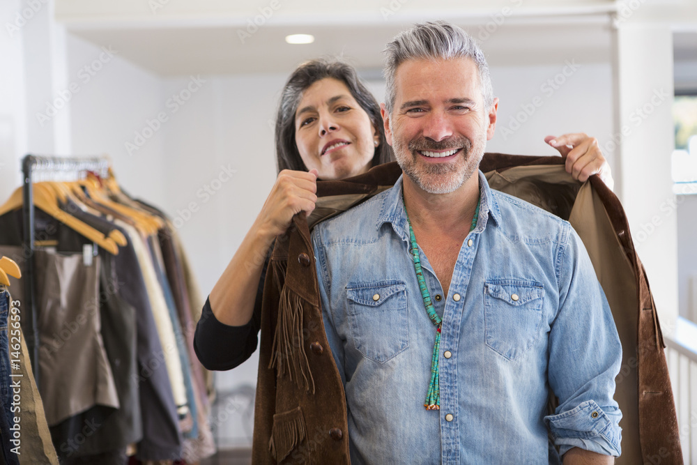Woman helping man with fringe jacket in store Woman helping man with fringe jacket in store