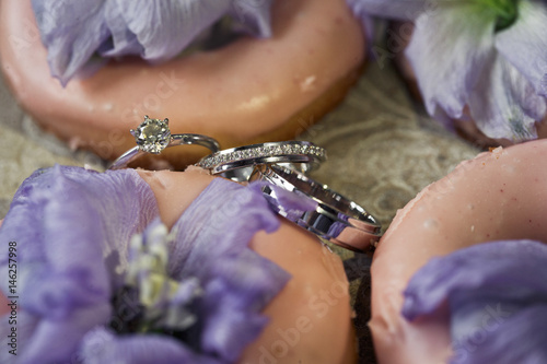 Wedding rings lie among pink cookies on the tray