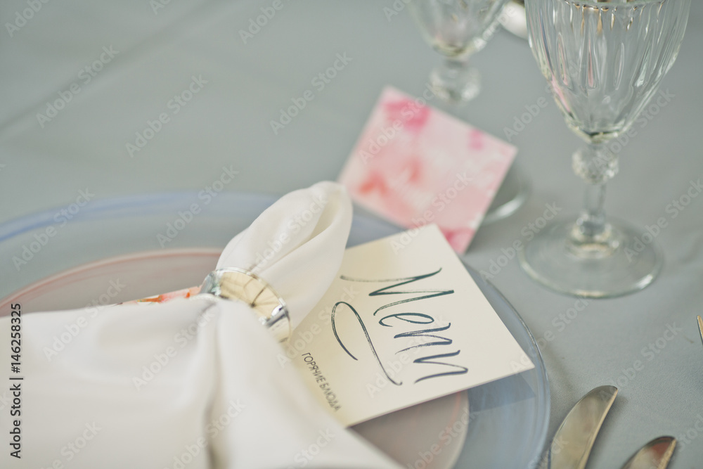 Card with lettering 'Menu' lies under white serviette on dinner plate Card with lettering 'Menu' lies under white serviette on dinner plate