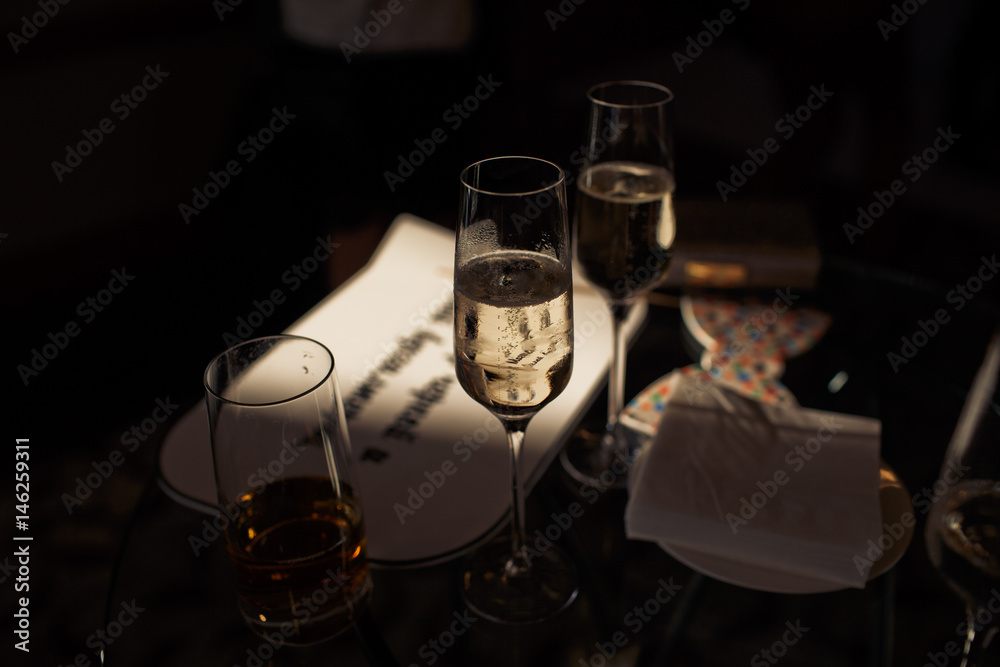 Champagne flutes stand in the darkness on dinner table