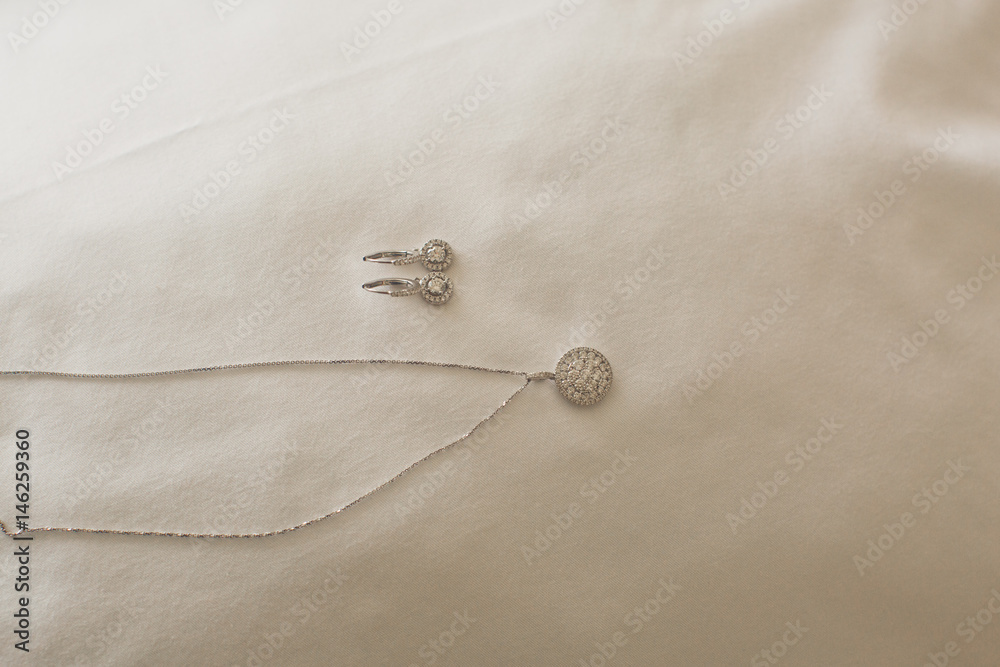 Crystal pendant and earrings lie on the white cloth Crystal pendant and earrings lie on the white cloth