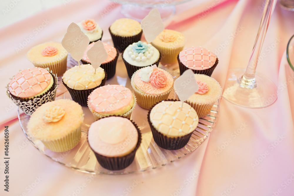 Tasty cupcakes covered with pink glaze stand on glass plate Tasty cupcakes covered with pink glaze stand on glass plate