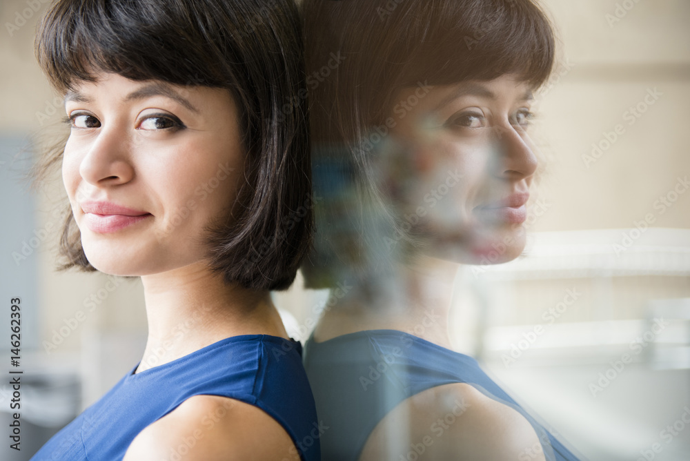 Reflection of Hispanic woman leaning on glass wall Reflection of Hispanic woman leaning on glass wall